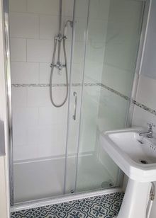 A traditional shower room, with a silver shower, and with a white wash basin.